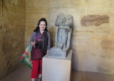 Laura stands beside headless granite statue of god Ptah at Ptah Temple, Karnak